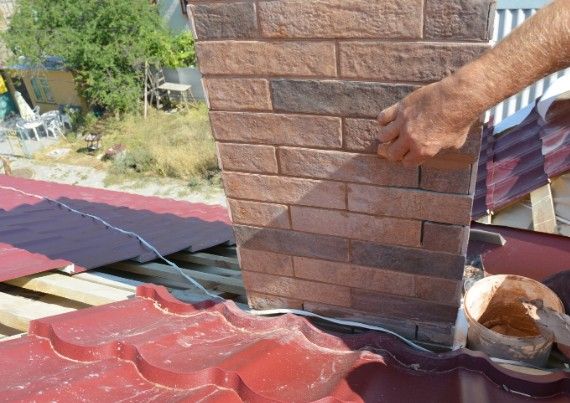 Revestimiento de chimenea con plaqueta Operario aplacando plaqueta de ladrillo sobre el cajón de una chimenea en la cubierta