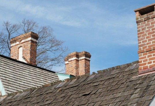 Dos chimeneas de ladrillo emergiendo de la cubierta de pizarra de una vivienda