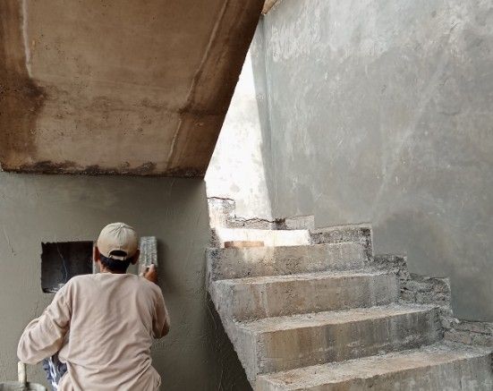 Enfoscado de caja de escalera Albañil enfoscando el paramento de una caja de escalera de hormigón en obra