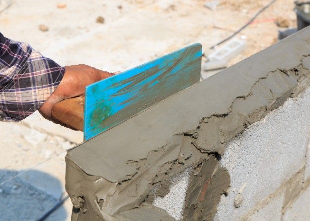 Enfoscado de mortero sobre muro de bloque Albañil enfoscando con llana la coronación de un muro de bloque de hormigón