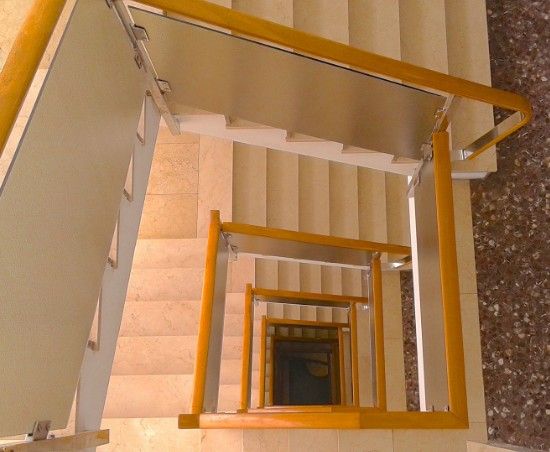 Escalera de comunidad de vecinos Hueco de escalera de una comunidad visto desde arriba, con peldaños de piedra y barandilla de madera