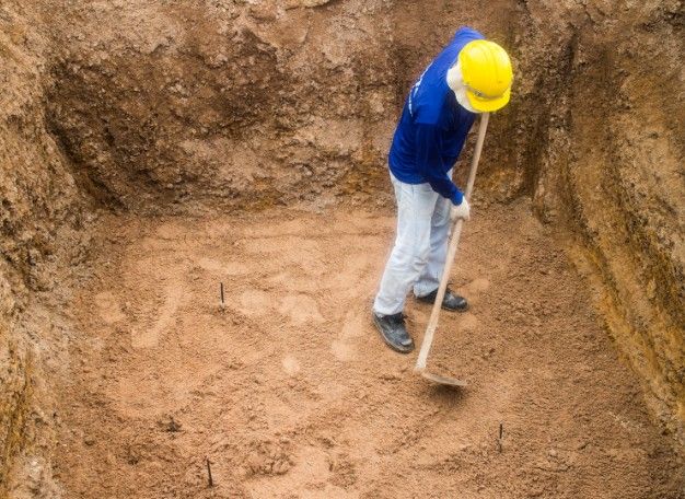Operario nivelando a mano el fondo excavado del vaso de una piscina de obra