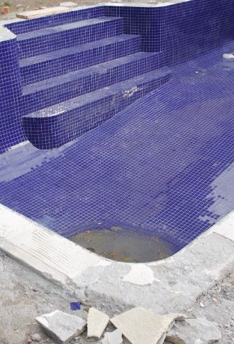 Revestimiento de gresite en el vaso Gresite azul recién colocado en la escalera y el fondo del vaso de una piscina
