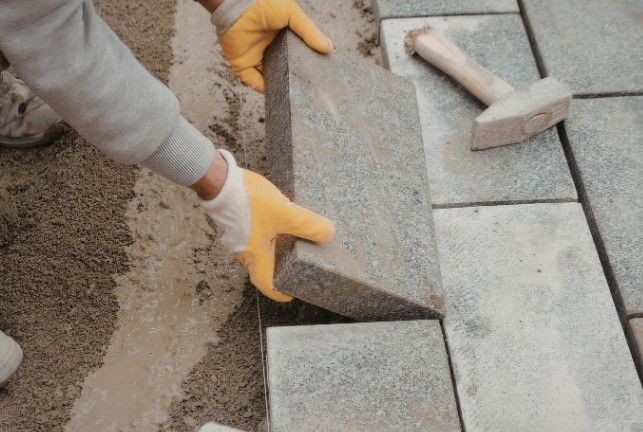 Losa de piedra sobre cama de mortero Albañil asentando una losa de piedra sobre la cama de mortero de un pavimento exterior