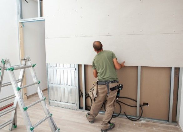 Instalador presentando una placa de pladur sobre la perfilería metálica de un trasdosado