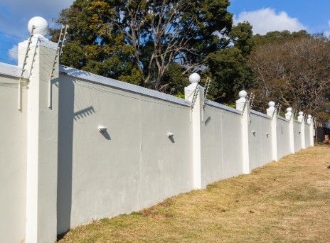 Muro de cerramiento con pilastras y albardilla Muro de cerramiento enfoscado y pintado, con pilastras rematadas y albardilla continua