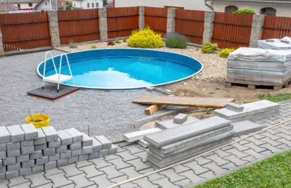 Entorno de piscina en ejecución Obra del entorno de una piscina con adoquinado, bordillos y muro de bloque a medio montar