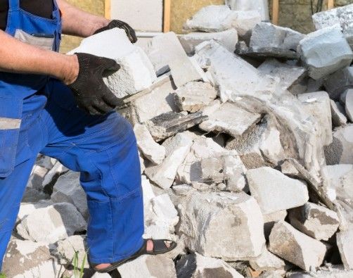 Retirada y separación de escombro Operario retirando a mano bloques de hormigón celular del montón de escombro de un derribo