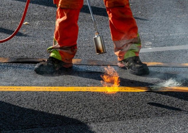 Sellado de banda asfáltica con soplete Operario sellando con soplete una banda asfáltica sobre el pavimento