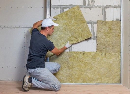 Operario encajando un panel de lana mineral en el trasdosado de un muro de bloque